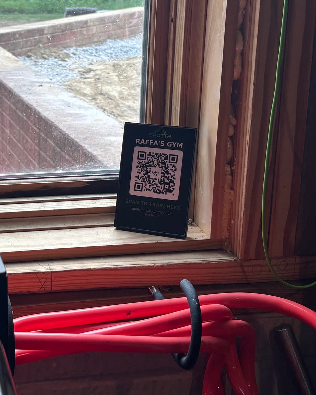 A SPOTTR scan-to-train QR placard standing on a windowsill at Raffa's Gym